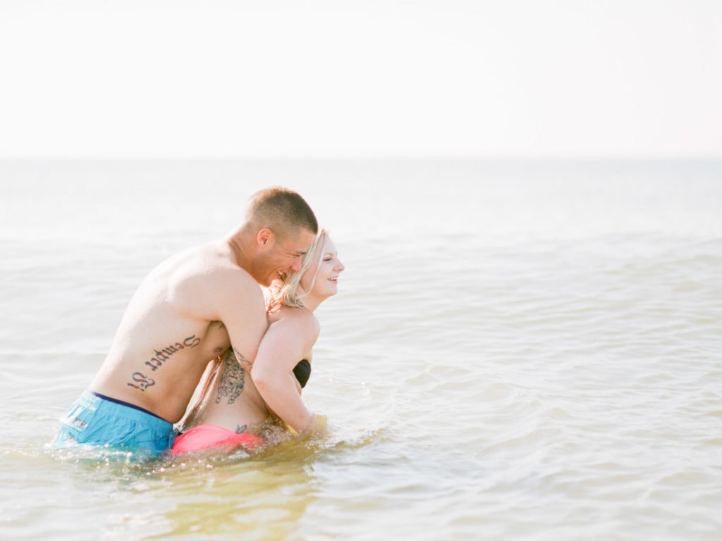couple has fun in the water after their engagement session