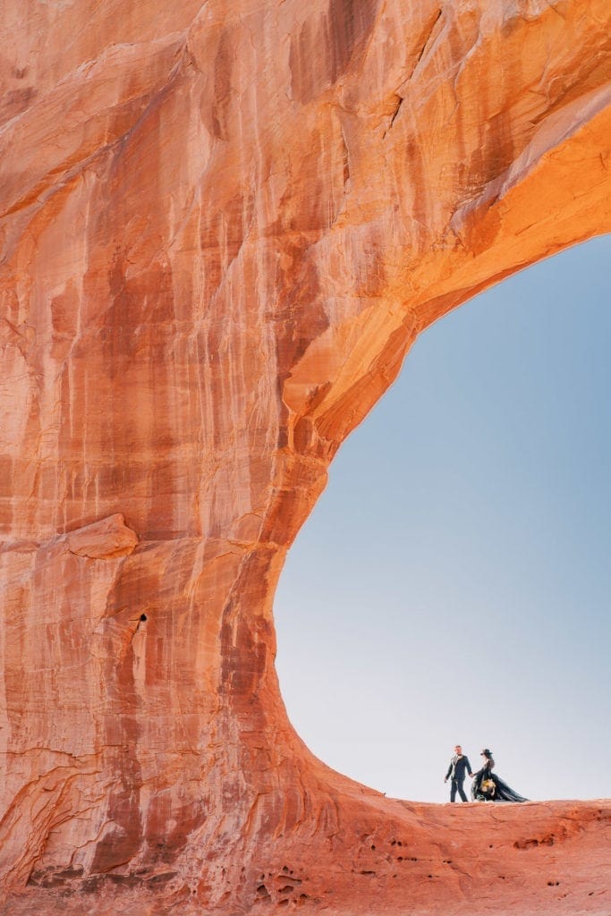 Elopement photography in Moab, Utah under an arch in the desert with a bride in a black dress.