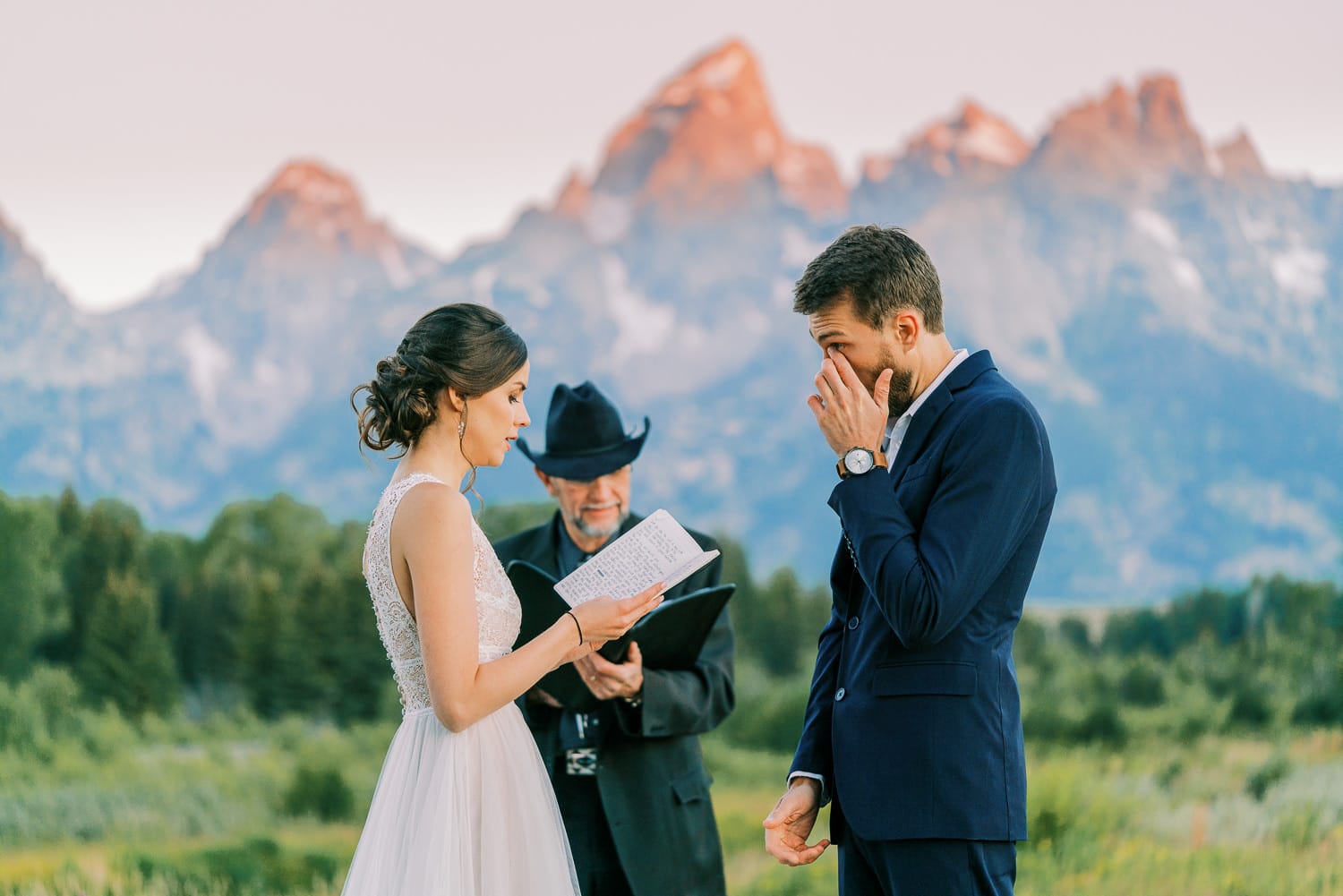 Groom wipes away tears at a wedding ceremony in Wyoming at sunrise.