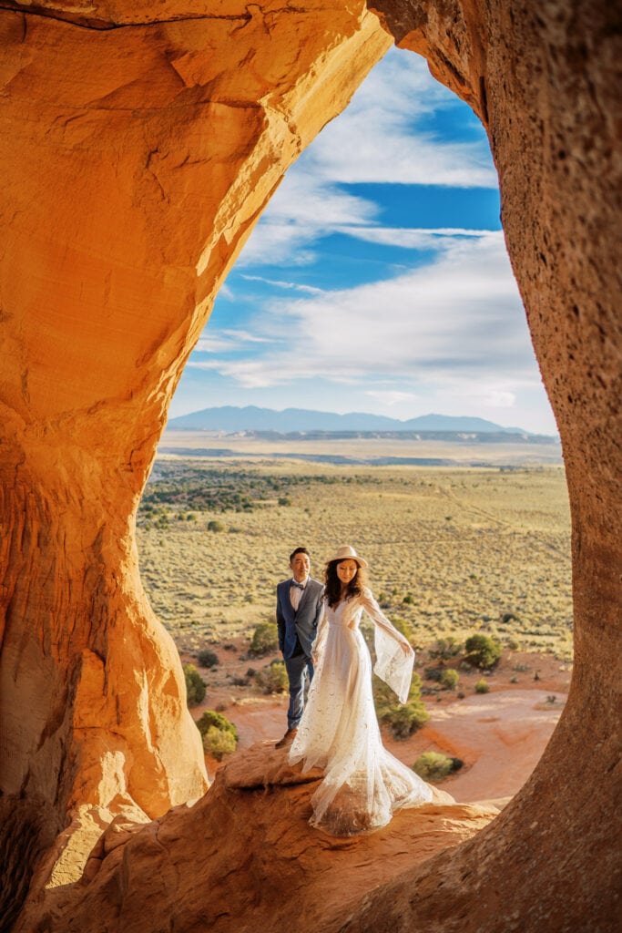 Bride and groom pose under a red rock arch in Moab, Utah.