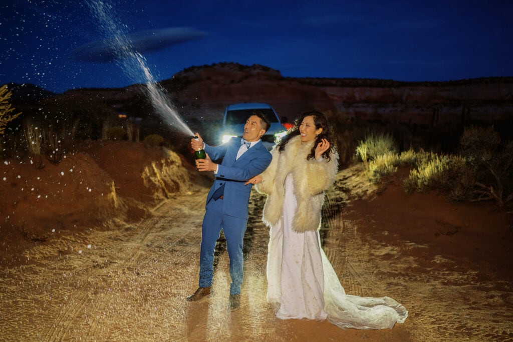 Bride and groom having a celebratory spray of champagne after their adventure elopement in Moab.