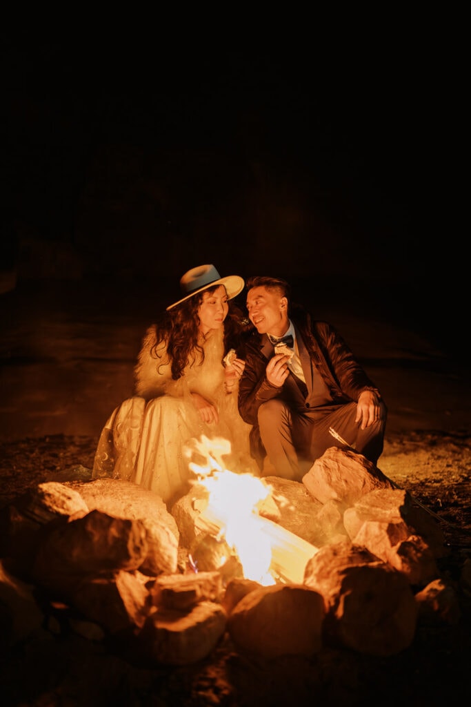 Bride and groom sitting by a campfire after their elopement day in Moab.