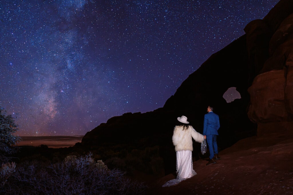 Bride and groom looking out at the Milky Way under the stars during their Moab adventure elopement.