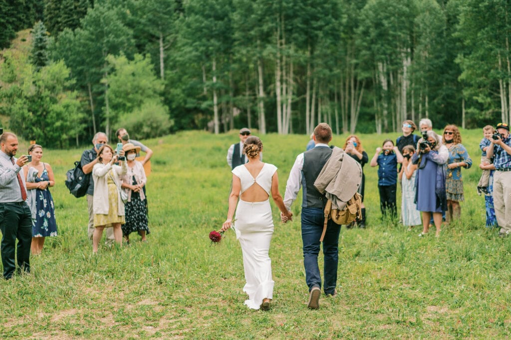 Bride and groom walk down the aisle together at their outdoor wedding in Ouray.