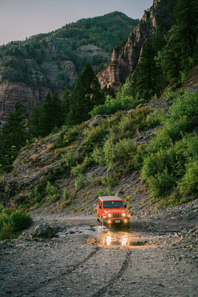 Bride and groom drive a Jeep in the mountains during their adventure elopement.