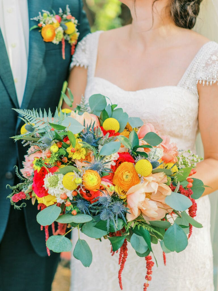 Bride holds a colorful jewel toned floral bouquet for her botanical gardens wedding in Tucson, Arizona.