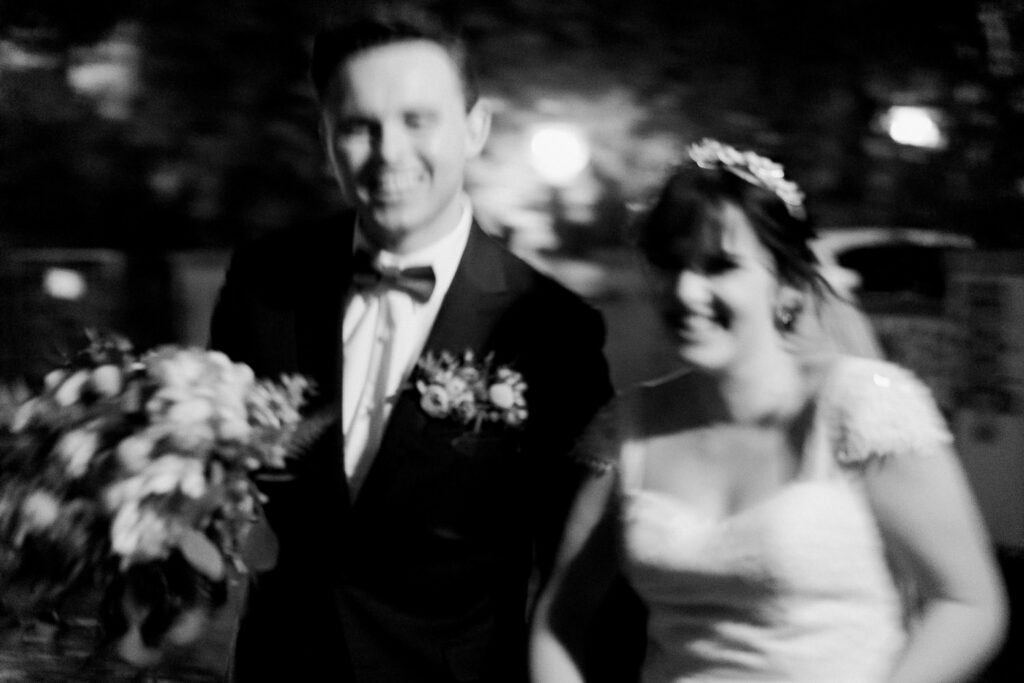 Creative black and white motion blur photography of a bride and groom running together.