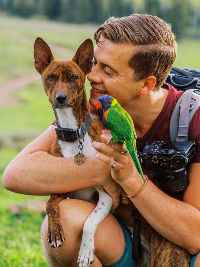 Malachi Lewis of Shell Creek Photography with a dog and a parrot.