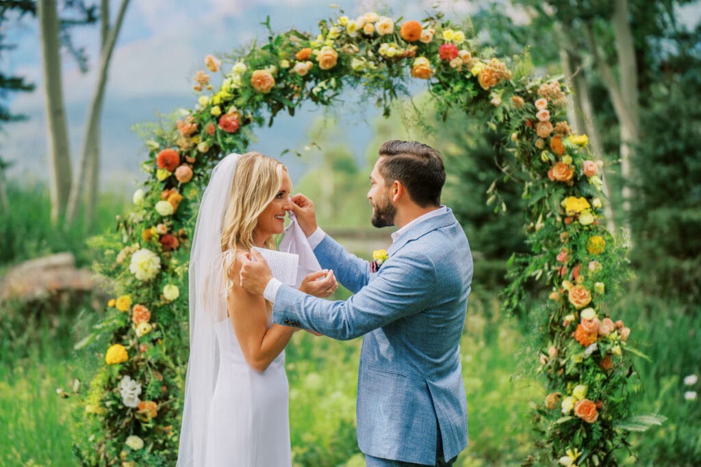 Groom wipes away tears from his bride during their vows at their Telluride, Colorado wedding in the mountains.