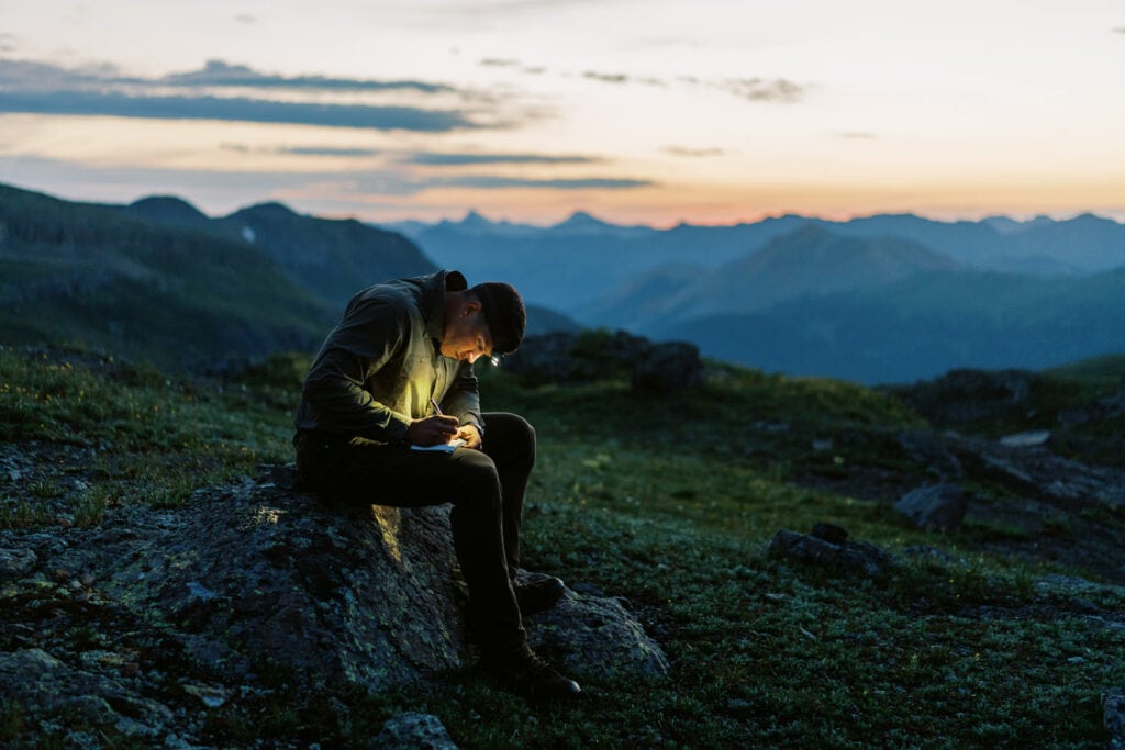 Groom writing his vows by headlamp just before sunrise in the mountains.