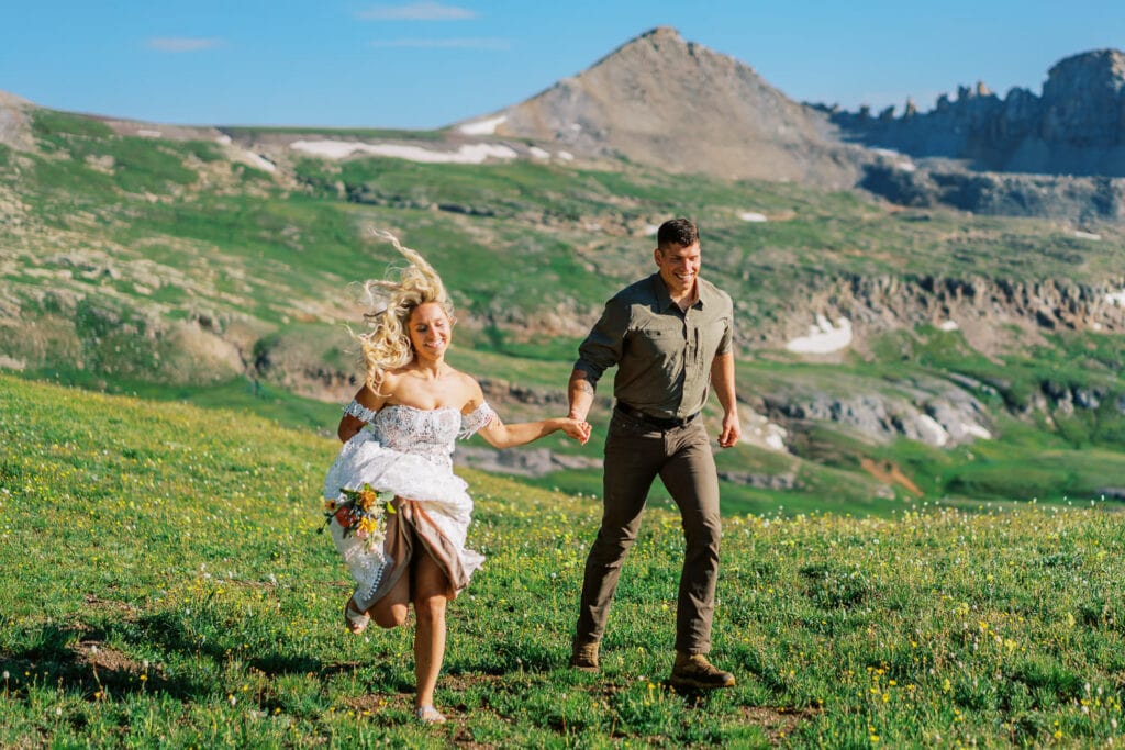 Bride and groom run through the mountains on their elopement day in the San Juan Mountains of Colorado.