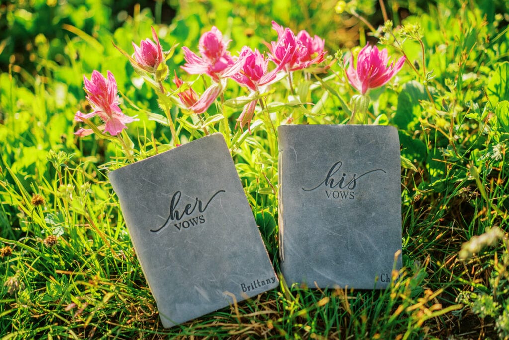 Bride and groom vow books with some wildflowers in the mountains of Colorado.