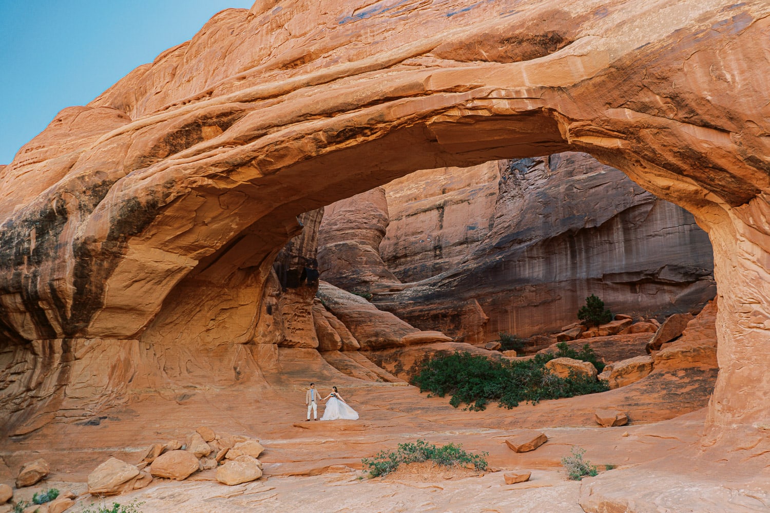 Couple under an arch during their elopement in Arches National Park.