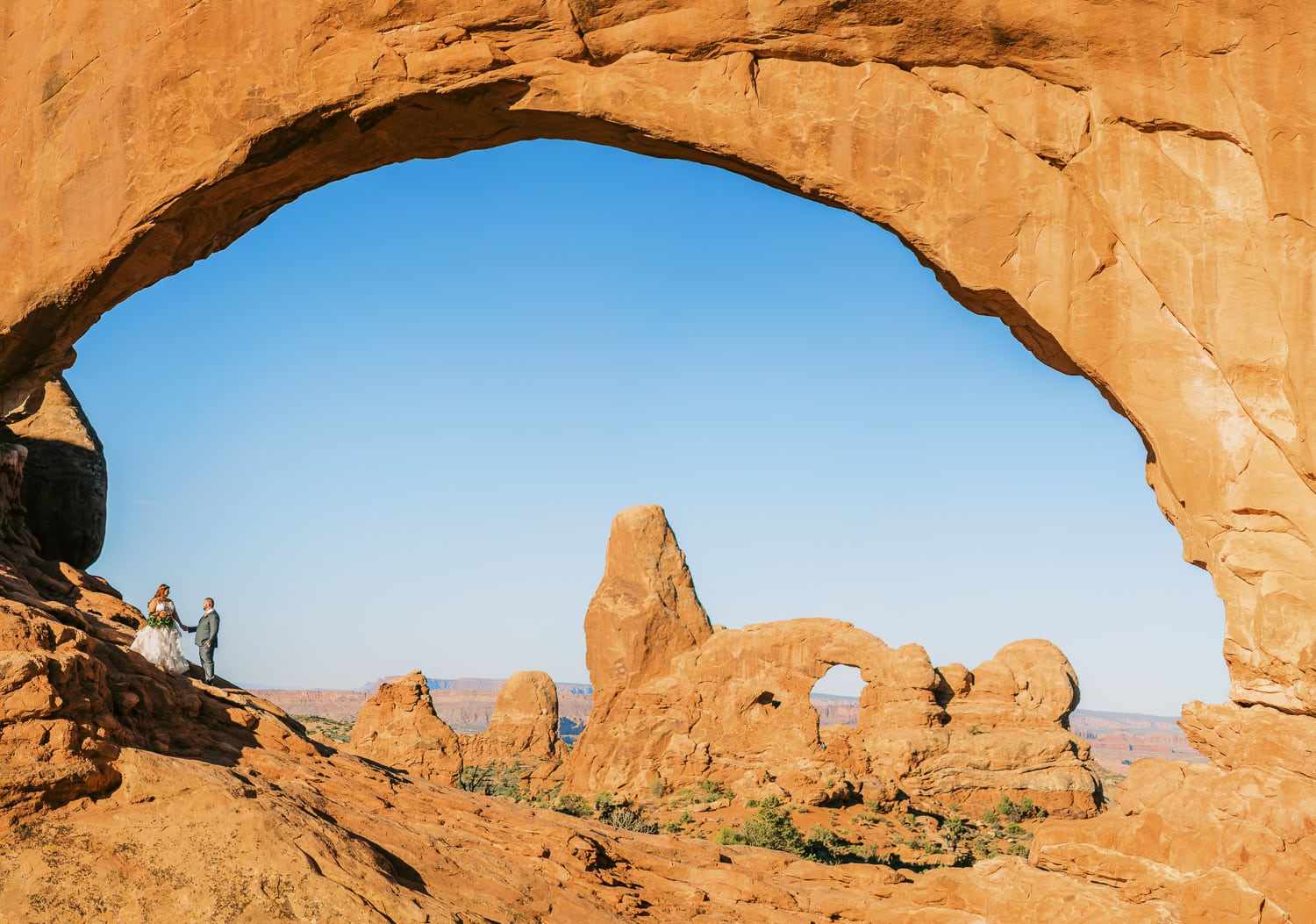 Sunrise elopement in Arches National Park under North Window with views of Turret Arch in the background.