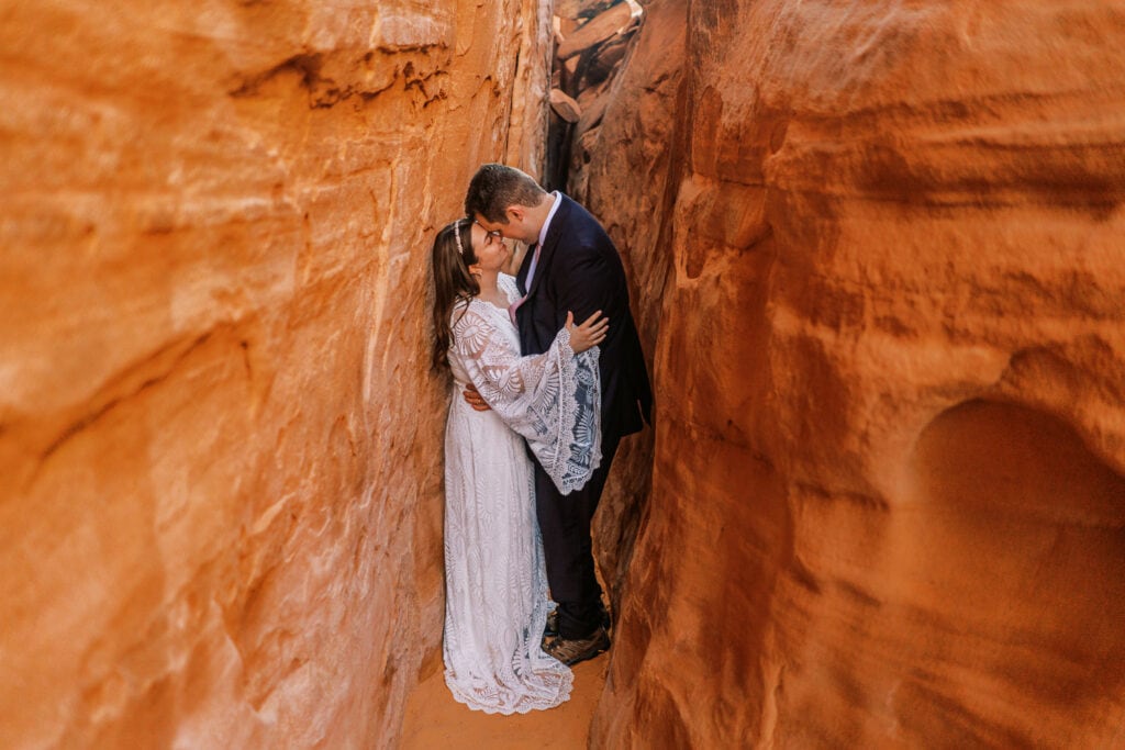 Bride and groom embrace in a slot canyon near Sand Dune Arch in Moab, Utah.