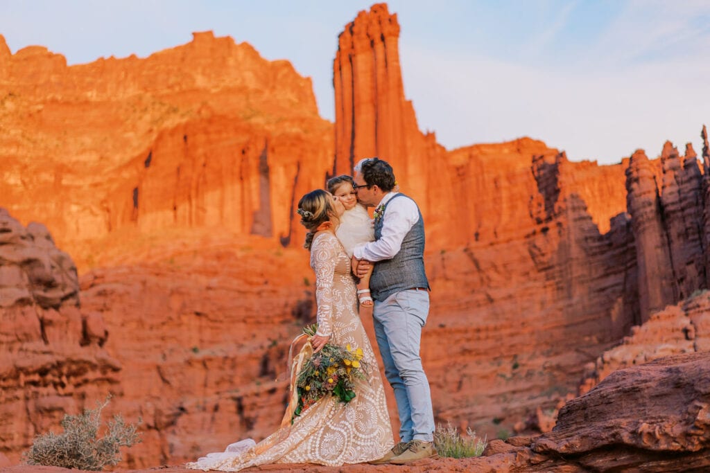 Bride and groom elope with their daughter at sunset in the deserts of Moab.