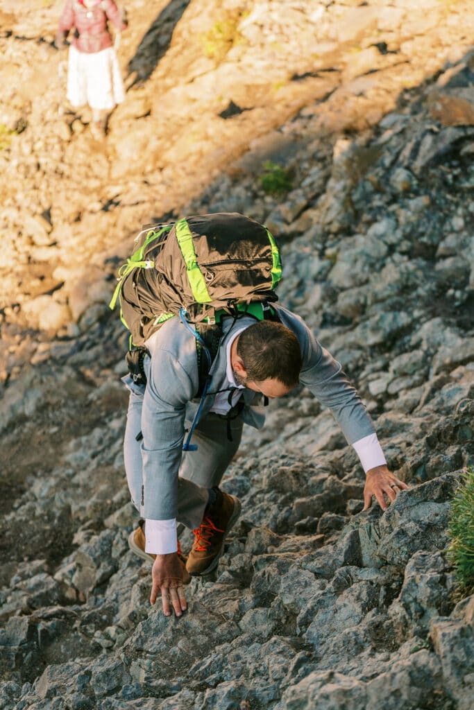 Groom climbing up rocks during an elopement near Silverton, Colorado.