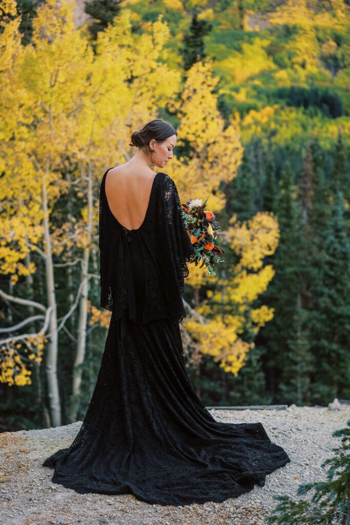 Bride in an elegant black wedding dress with a dark floral bouquet.