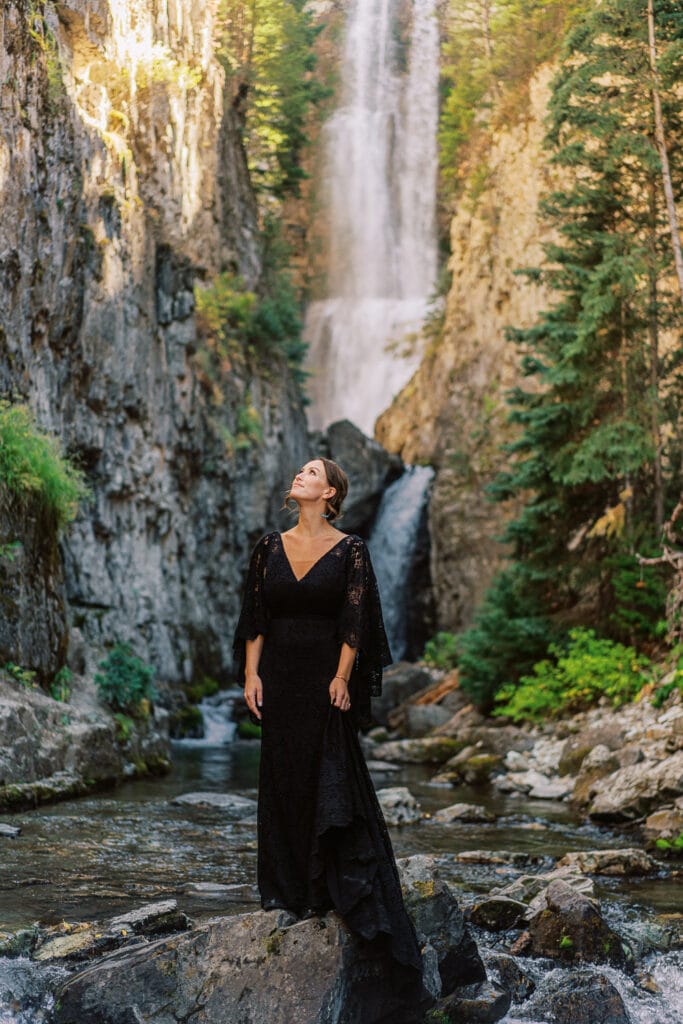 Portrait of a bride in a custom black wedding dress at a waterfall in Colorado.