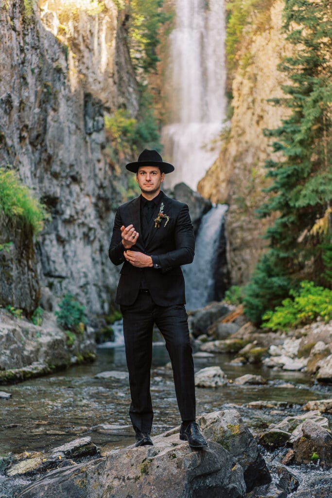 Portrait of a groom at a waterfall during an adventure wedding in the mountains.