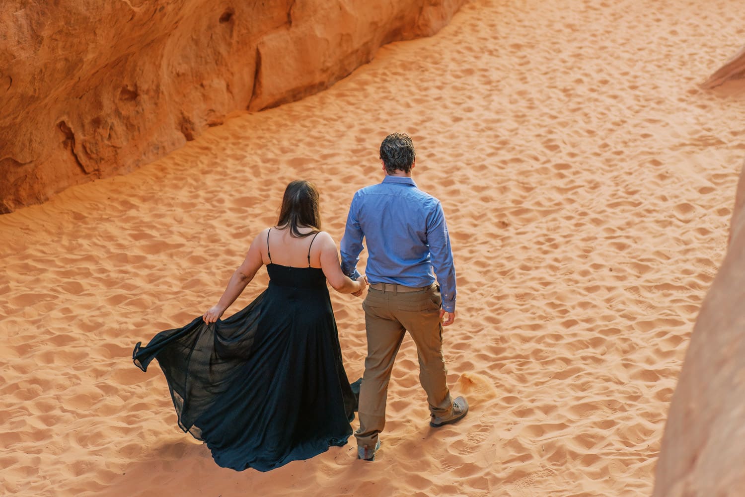 Couple walks together in the desert of Moab for engagement photos.