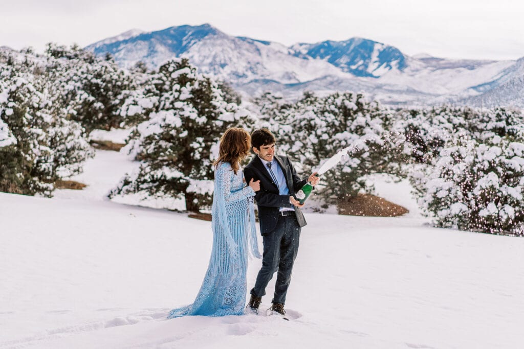 Bride and groom spraying champagne at the end of their elopement in Moab.