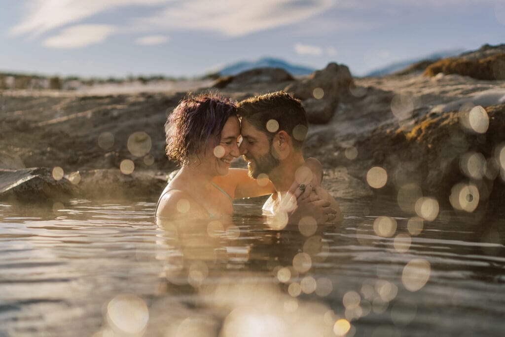Hot spring elopement in California with a bride and groom snuggling in a natural hot spring.