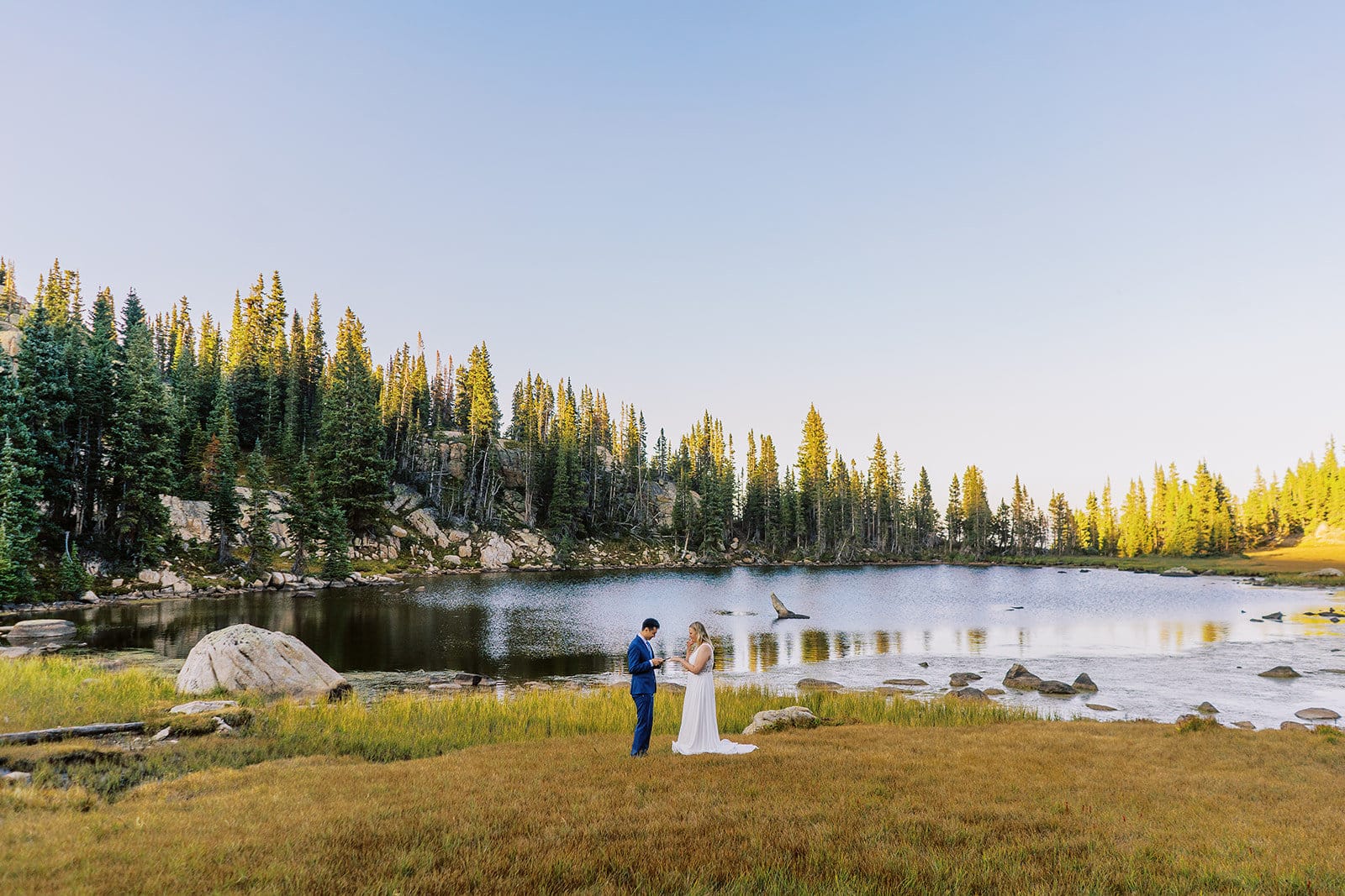 Bride and groom share vows together at their sunset elopement ceremony in Bend, Oregon near a lake in the forest.