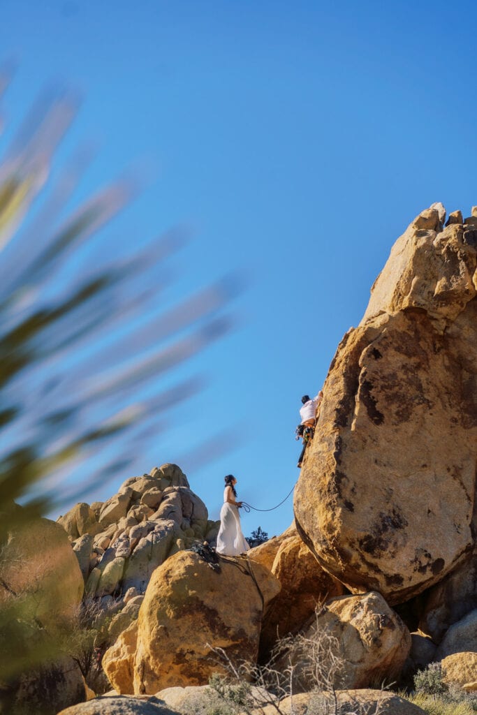 Bride and groom climbing together for their elopement day in Joshua Tree National Park.
