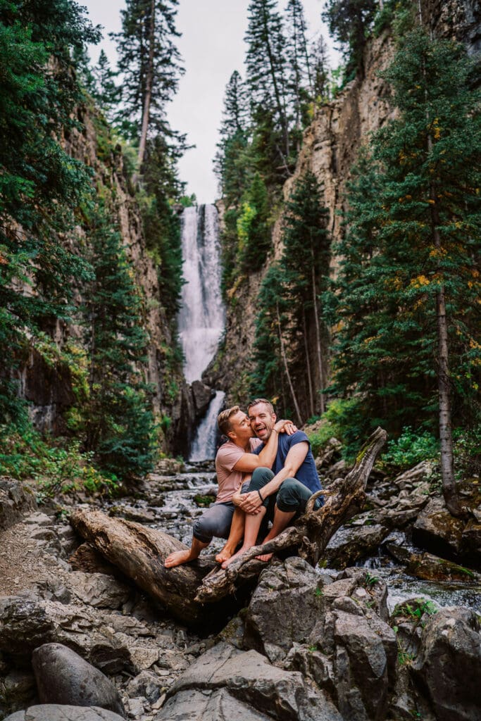 Two guys kissing under a waterfall during a same sex engagement session in Colorado.